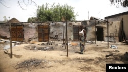 Une femme devant des maisons incendiées après une explosion provoquée par des combattants de Boko Haram dans l'Etat d'Adamawa , le 10 mai 2015, au Nigeria.