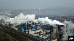 Asap dan uap dari pabrik pemrosesan batu bara yang menghasilkan karbon hitam, bahan dalam pembuatan baja, di Hejin di Provinsi Shanxi, China tengah, 28 November 2019. (AP Photo/Sam McNeil)