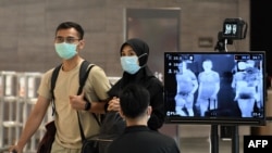 싱가포르 창이 국제공항 이용객들이 마스크를 쓴 채 발열 점검 기구를 통과하고 있다. (자료사진)