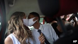 Wearing masks to prevent the spread of the new coronavirus, Thiago do Nascimento, right, and Keilla de Almeida kiss during their drive-thru wedding at the registry office in the neighborhood of Santa Cruz, Rio de Janeiro, Brazil, May 28, 2020.