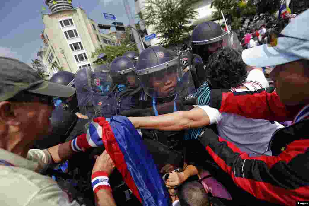 Policemen charge against anti-government protesters at one of their barricades near the Government House, Bangkok, Feb. 18, 2014.