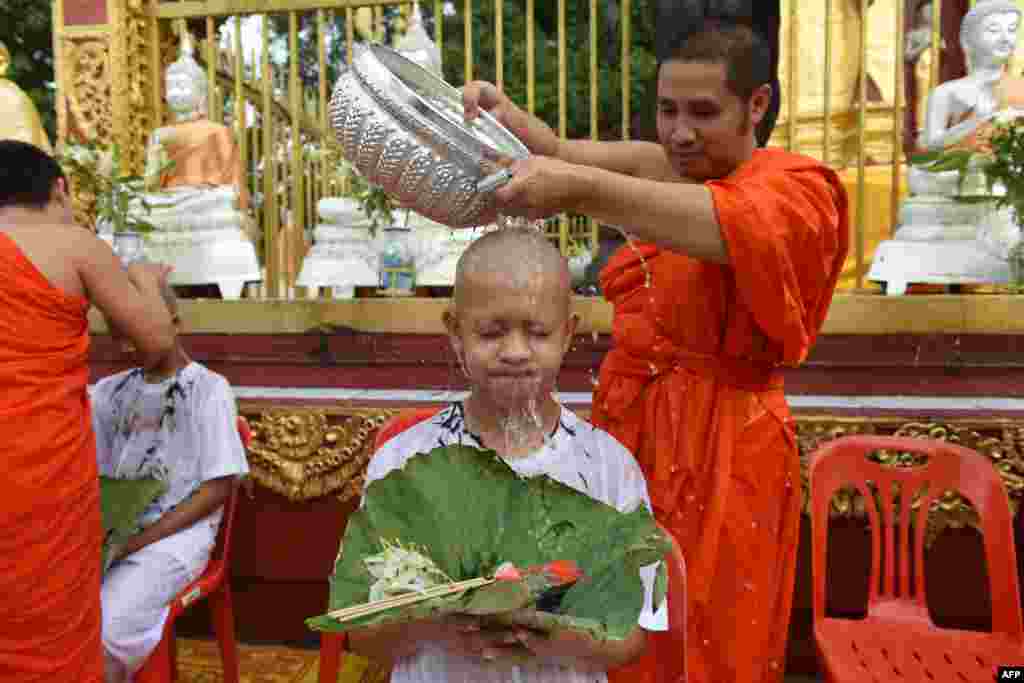 ព្រះសង្ឃពុទ្ធសាសនាមួយអង្គស្រោចទឹកកុមារាជនជាតិថៃនៃក្រុមបាល់ទាត់«Wild Boars» បន្ទាប់ពីត្រូវបានកោរសក់រួចនៅវត្ត Phra That Doi Wao ស្រុក Mae Sai ខេត្តឈៀងរ៉ៃ។