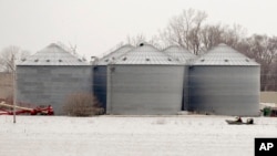 Utility workers travel by boat past grain bins in the flooded town of Pacific Junction, Iowa, April 3, 2019. 