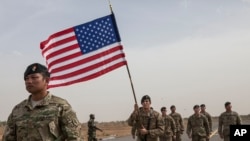 Un militaire américain porte le drapeau américain devant une cohorte de ses camarades et compatriotes à la cérémonie d'ouverture de Flintlock, des exercices contre le terrorisme à Thiès, au Sénégal, 8 février 2016. 