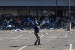 A member of the South African Police Services (SAPS) fires rubber bullets at rioters looting the Jabulani Mall in Soweto, southwest of Johannesburg, July 12, 2021.