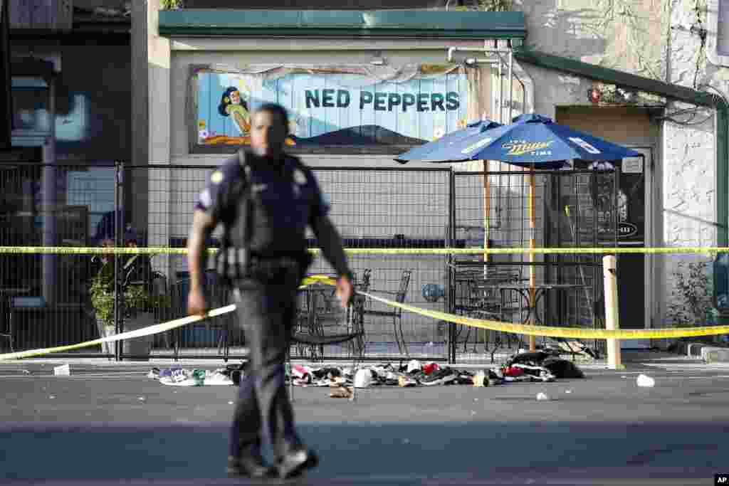 Un policía camina frente al bar Ned Peppers, en Dayton, Ohio, escenario de un tiroteo masivo, ocurrido menos de 24 horas de uno anterior en El Paso, Texas. Nueve personas murieron en el ataque de Ohio, además del responsable que fue abatido por la policía. (AP Photo/John Minchillo)