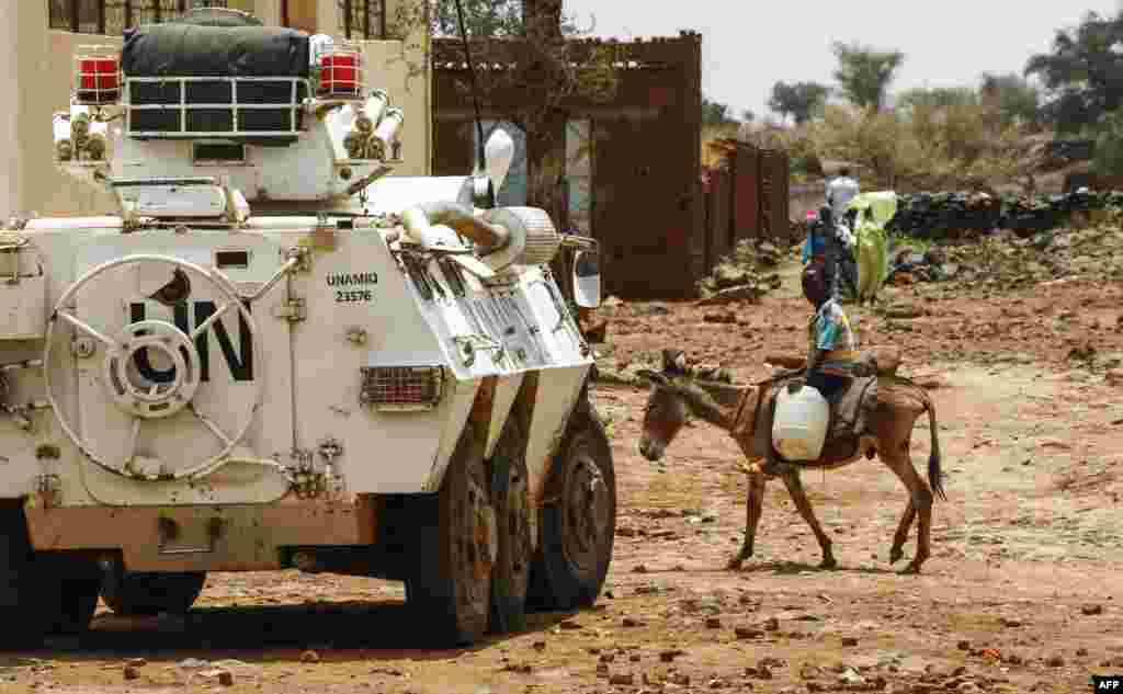 A Sudanese boy rides a donkey past a UN-African Union mission in Darfur (UNAMID) armoured vehicle in the war-torn town of Golo in the thickly forested mountainous area of Jebel Marra in central Darfur.