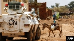 Un garçon conduit un âne devant un blindé de la mission des Nations unies et de l'Union africaine au Darfour (MINUAD) dans la ville de Golo, au Darfour, Soudan, le 19 juin 2017. AFP PHOTO / ASHRAF SHAZLY
