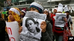 Para pembantu rumah tangga dan pendukung mereka memegang gambar TKI Erwiana Sulistyaningsih, 23, yang diduga disiksa majikannya di Hong Kong, Maret 2014. (AP/Vincent Yu)