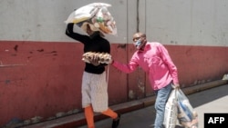 FILE - A woman walks with her blind husband as they carry food collected during a food distribution leaded by the international NGO Gift to the Givers, in Johannesburg, South Africa, Oct. 14, 2020.