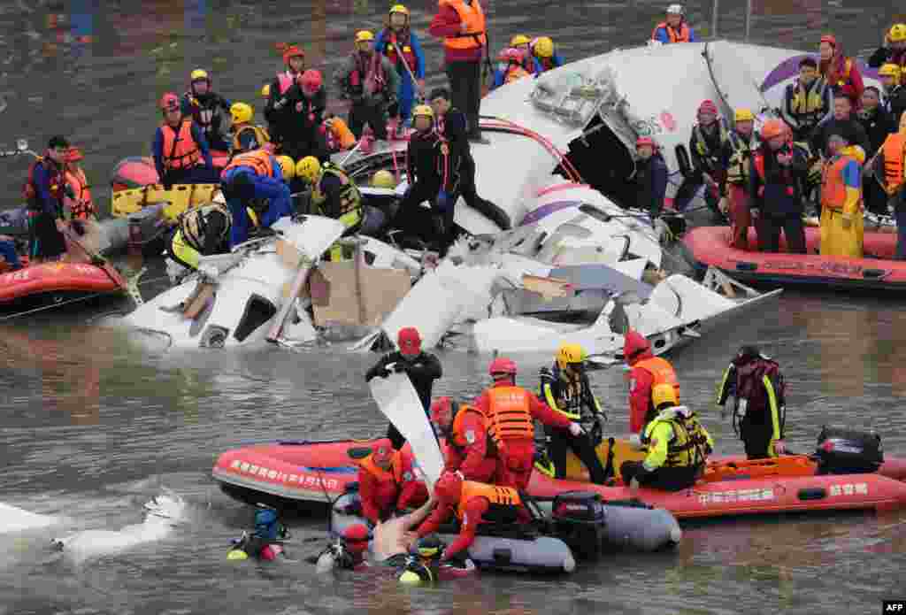 Rescue personnel in a rubber dinghy lift a passenger (bottom C) from the waters around the wreckage of a TransAsia ATR 72-600 turboprop plane that crash-landed into the Keelung river outside Taiwan's capital Taipei in New Taipei City.