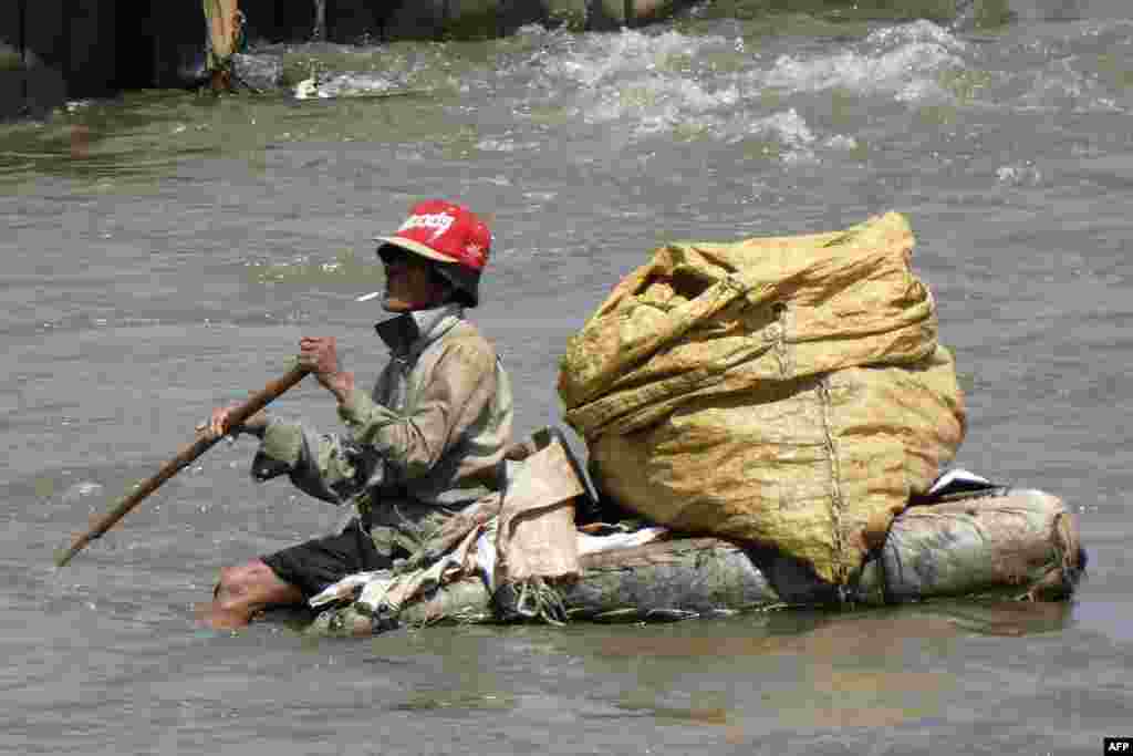 Seorang pemulung mencari barang-barang yang masih bisa didaur ulang di sebuah sungai di Jakarta.