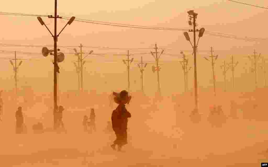 Umat Hindu di India berjalan menembus badai pasir di Sangam setelah berendam di sungai Ganges, Yamuna dan Saraswati pada festival Maha Kumbh di Allahabad.