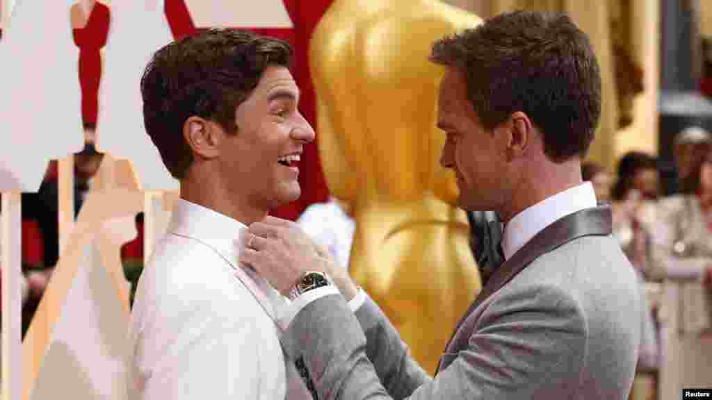 L'hôte des Oscars, Neil Patrick Harris, ajuste la cravate de son mari David Burtka (G) à leur arrivée à la cérémonie des 87e Oscars à Hollywood, Californie, le 22 février 2015.