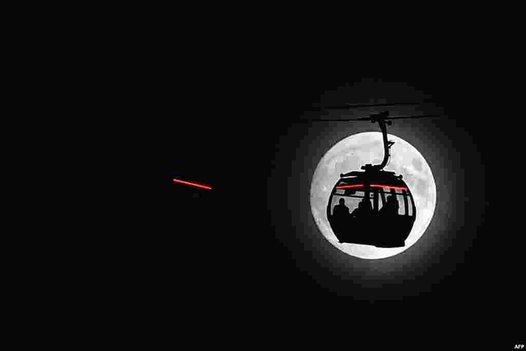 The moon rises behind a cable car in London's Docklands. Tomorrow, the moon will orbit closer to the earth than at any time since 1948, named a 'supermoon.'