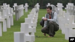Matthew Conway, de Burlington, Connecticut, coloca una flor en la tumba de su tío John J. Ketter, en el cementerio militar estadounidense Colleville, en Colleville sur Mer, en el oeste de Francia, el miércoles, 6 de junio de 2018.