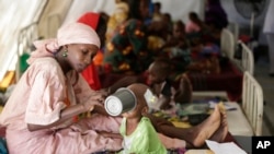 Une femme nourrit un enfant dans un centre hébergeant près de 75.000 personnes qui ont fui les attaques de Boko Haram à Maiduguro, Nigeria, 29 août 2016.