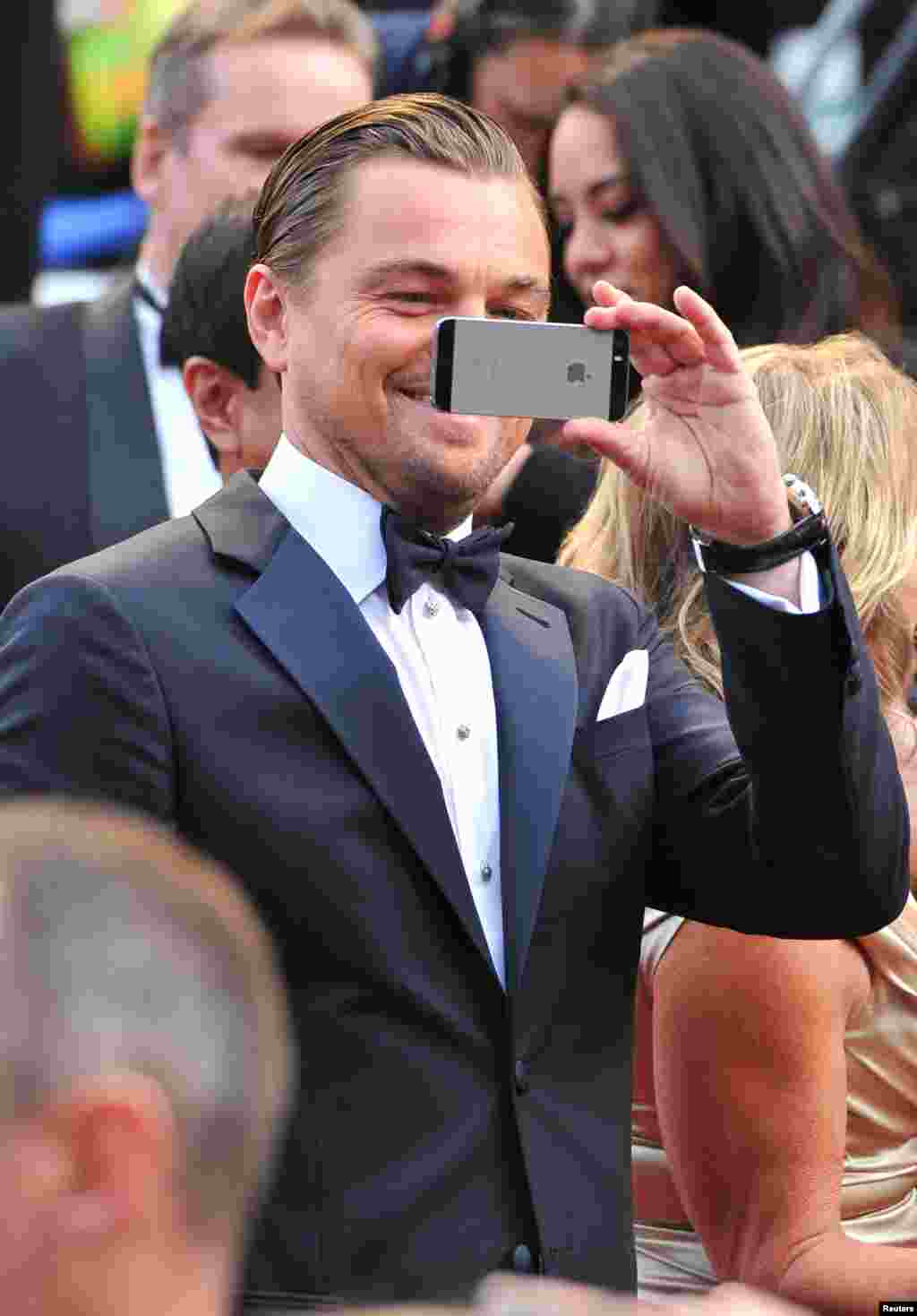 Aktor Leonardo DiCaprio memotret dengan ponselnya saat tiba di karpet merah Academy Awards ke-86 di Dolby Theatre, Los Angeles. (AP/Vince Bucci)