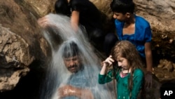 ARSIP - Sebuah keluarga mendinginkan diri di sungai selama gelombang panas yang melanda, di Islamabad, Pakistan, tanggal 30 Mei 2017. Kota Turbat di baratdaya Pakistan mencatat suhu setinggi 54 derajat Celsius pada bulan Mei (foto: B.K. Bangash/AP Photo)