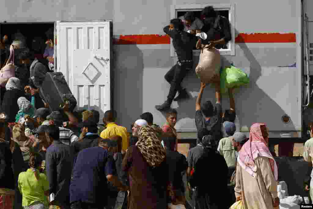 Syrians refugees try to enter a truck which will transport them back to their homeland at the Al-Zaatri refugee camp, Mafraq, near the border with Syria, July 30, 2013. 