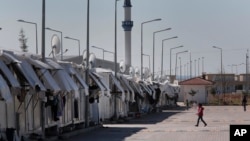 Refugees walk at the Oncupinar refugee camp for Syrian refugees next to the border crossing with Syria, near the town of Kilis in southeastern Turkey, Thursday, March 17, 2016. (AP Photo/Lefteris Pitarakis)
