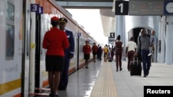 FILE - A man carries an infant as he walks along the platform in front an SGR train traveling to Mombasa from the Nairobi SGR Terminus, outside Nairobi, Kenya, October 22, 2019. 