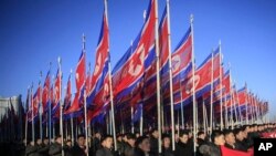 朝鲜人手举国旗在平壤金日成广场游行向朝鲜劳动党表忠诚.(2016年2月25日)