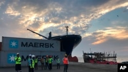 Des employé se tiennent devant des conteneurs d'expédition au port de Berbera, à Berbera, Somaliland, Somalie, le 1 avril 2018.