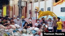 Manifestantes se esconden tras una barricada en el distrito Sanchaung, en Rangún, Myanmar. Lunes 8 de marzo de 2021.