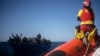 Des migrants sont aidés par des travailleurs humanitaires de l'ONG espagnole Open Arms, après avoir fui la Libye à bord d'une embarcation précaire en mer Méditerranée, à environ 110 miles au nord de la Libye, le 2 janvier 2021.