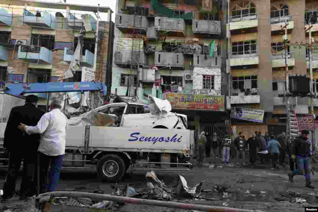 People look at the site of a car bomb attack in Baghdad, Jan. 20, 2014.