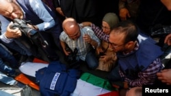 Waombolezaji, wakiwemo waandishi wa habari waonekana karibu na maiti ya mwandishi wa Al Jazeera Shireen Abu Akleh, aliyeuawa kwa kupigwa risasi na jeshi la Israel kwa mujibu wa Al Jazeera, May 11, 2022. Picha ya Reuters.