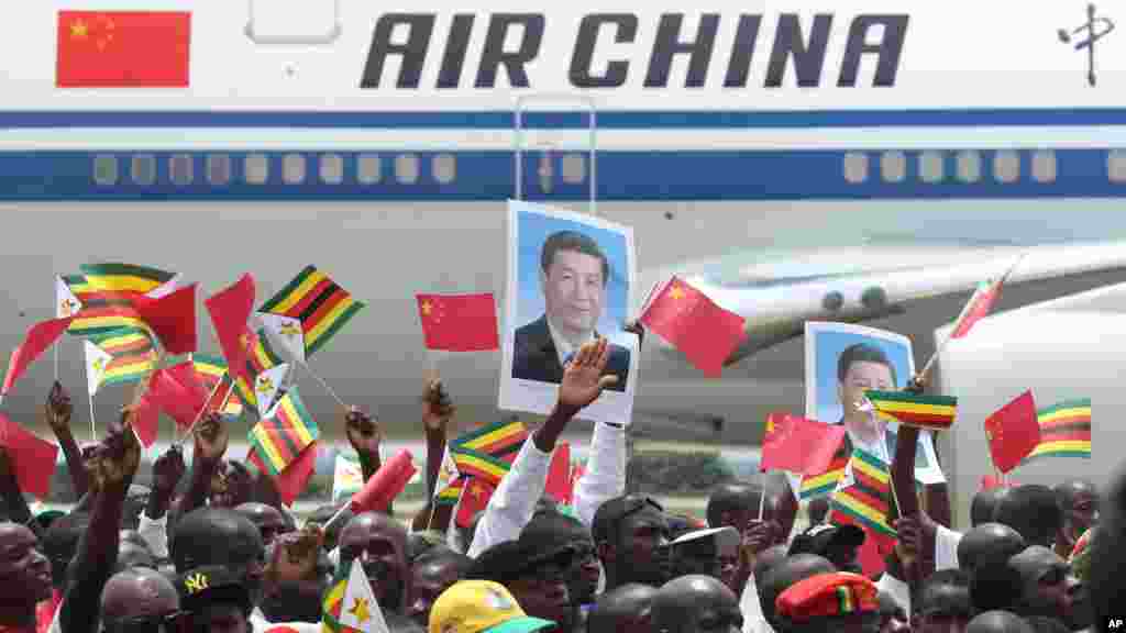 Zimbabweans wave flags while welcoming Chinese President Xi Jinping in Harare, Zimbabwe, Tuesday, Dec. 1, 2015. Jinping is in Zimbabwe for a two day State visit during which he is set to sign some bilateral agreements aimed at strengthening relationships between the two countries.