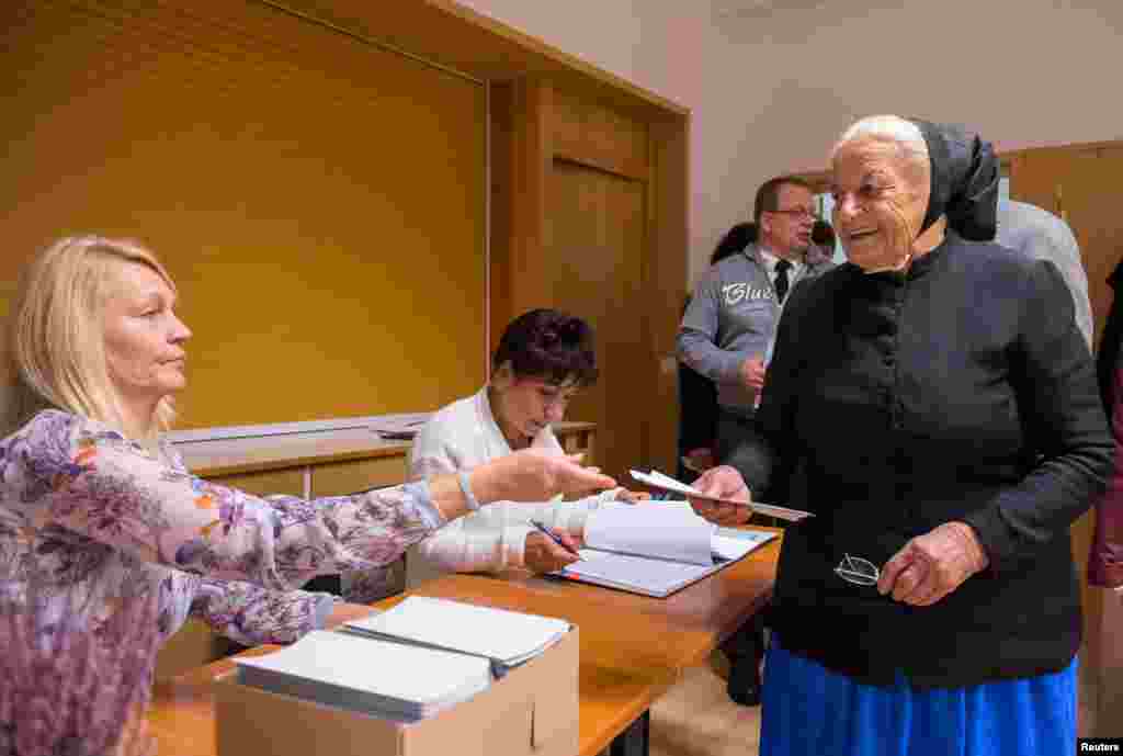 A woman wearing traditional Sorb clothing casts her vote in a polling station in Crostwitz, eastern Germany, Sept. 24, 2017.
