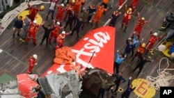 Rescuers wave at an Indonesian Air Force helicopter near portion of AirAsia Flight 8501 after it was recovered from the sea floor on the deck of a rescue ship on the Java Sea, Saturday, Jan. 10, 2015.