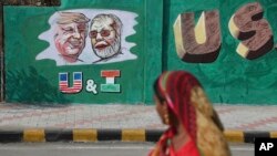 An Indian woman looks at a wall painted with portraits of U.S. President Donald Trump and Indian Prime Minister Narendra Modi ahead of Trump's visit, in Ahmadabad, India, Feb. 18, 2020.