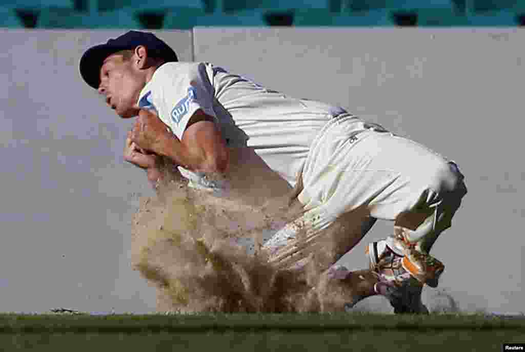 Cricket Australia Invitational XI player Daniel Hughes kicks up dirt as he takes a catch to dismiss England's Kevin Pietersen for 57 runs during their warm-up match at the Sydney Cricket Ground, Australia.