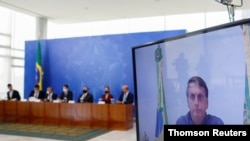 El presidente de Brasil, Jair Bolsonaro aparece en una pantalla durante una videoconferencia sobre un marco legal de sanidad, en el Palacio de Planalto, Brasilia, el 15 de julio de 2020.