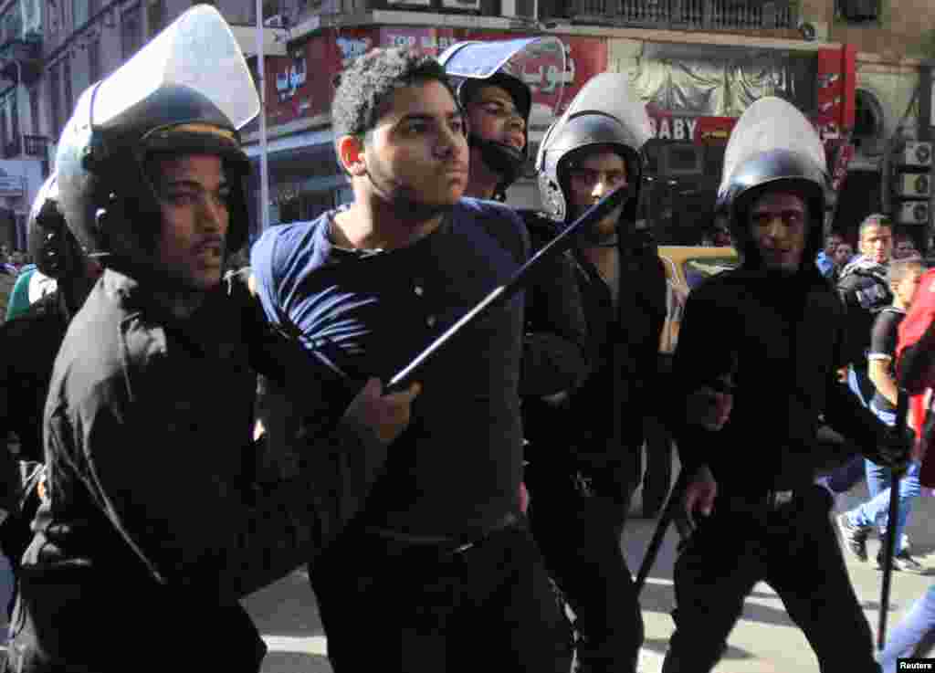 Riot police detain a man who was taking part in a protest against a new law in Egypt that restricts demonstrations, in downtown Cairo, Nov. 26, 2013.