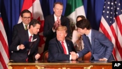 Donald Trump serre la main du premier ministre canadien Justin Trudeau, sous le regard du président du Mexique, Enrique Peña Nieto, après la signature de l'accord en Argentine, le 30 novembre 2018.