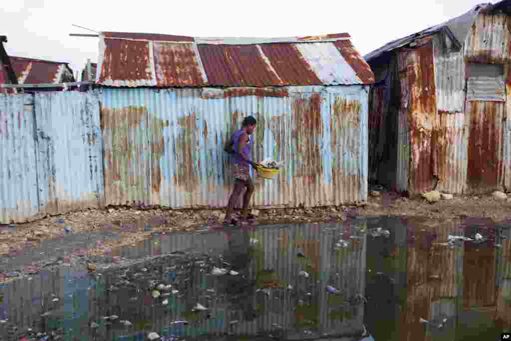 A woman skirts a puddle as she walks home in the seaside slum of Port-au-Prince, Haiti, Sept. 6, 2017.