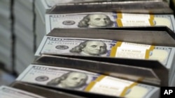 FILE - Freshly-cut stacks of $100 bills make their way down the line at the Bureau of Engraving and Printing Western Currency Facility in Fort Worth, Texas, Sept. 24, 2013.