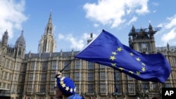 An anti-Brexit campaigner shows her support for Europe waving a European Union flag outside Parliament in London, March 25, 2019. 