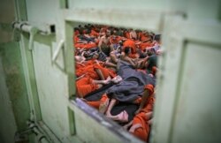 FILE - Men suspected of being affiliated with the Islamic State group are seen in a prison cell in the northeastern Syrian city of Hasakeh, Oct. 26, 2019.