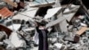 A Palestinian woman reacts near the rubble of a building housing The Associated Press, broadcaster Al-Jazeera and other media outlet, in Gaza City. The building was destroyed by an Israeli airstrike on Saturday.