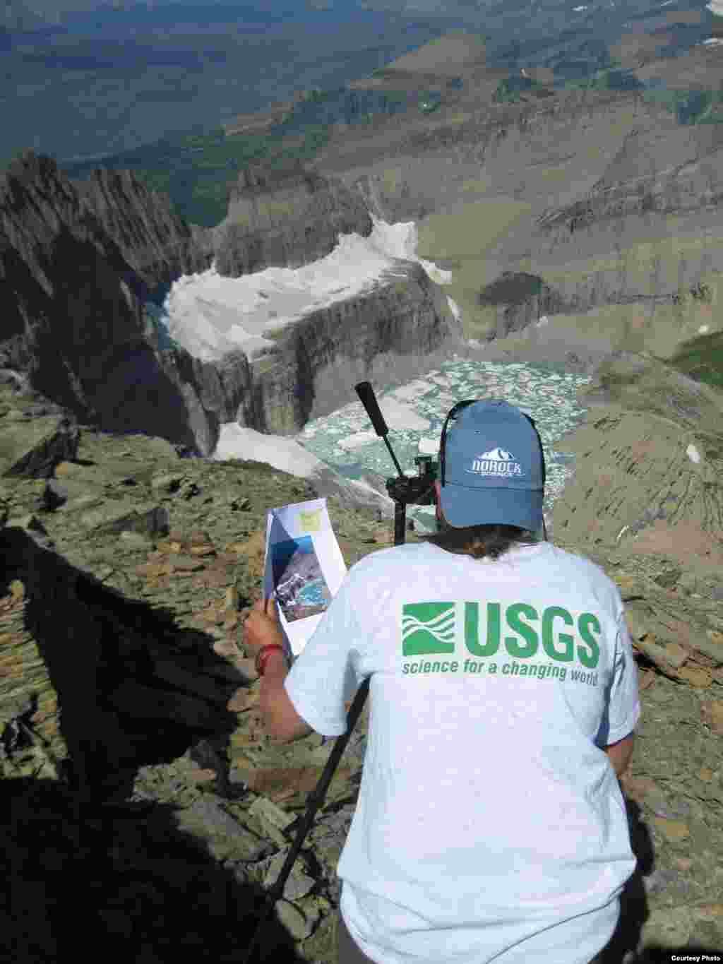 A USGS scientist shoots a repeat photograph of Grinnell Glacier in Glacier National Park to illustrate glacial recession due to impacts of climate change. (Lisa McKeon, Northern Rocky Mountain Science Center)