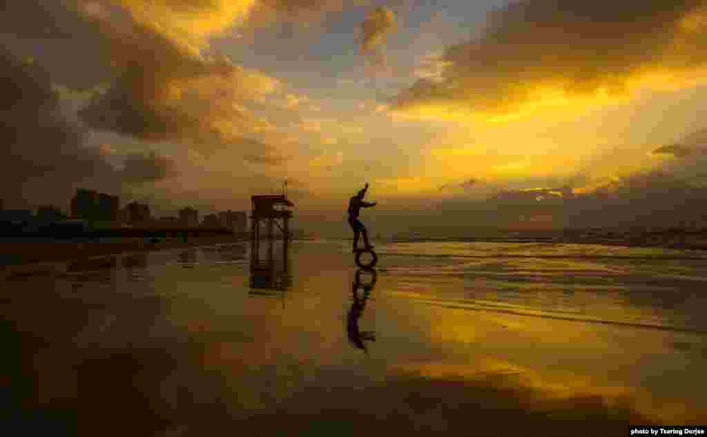 Un jeune palestinien en équilibre sur un pneu sur la plage au coucher du soleil à Gaza, le 24 décembre 2017.