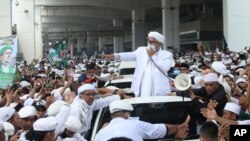 File - Indonesian Islamic cleric and the leader of Islamic Defenders Front Rizieq Shihab, center, speaks to his followers upon arrival from Saudi Arabia at Soekarno-Hatta International Airport in Tangerang, Indonesia, Nov. 10, 2020.