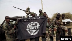 Nigerian soldiers hold up a Boko Haram flag seized in the town of Damasak, Nigeria.