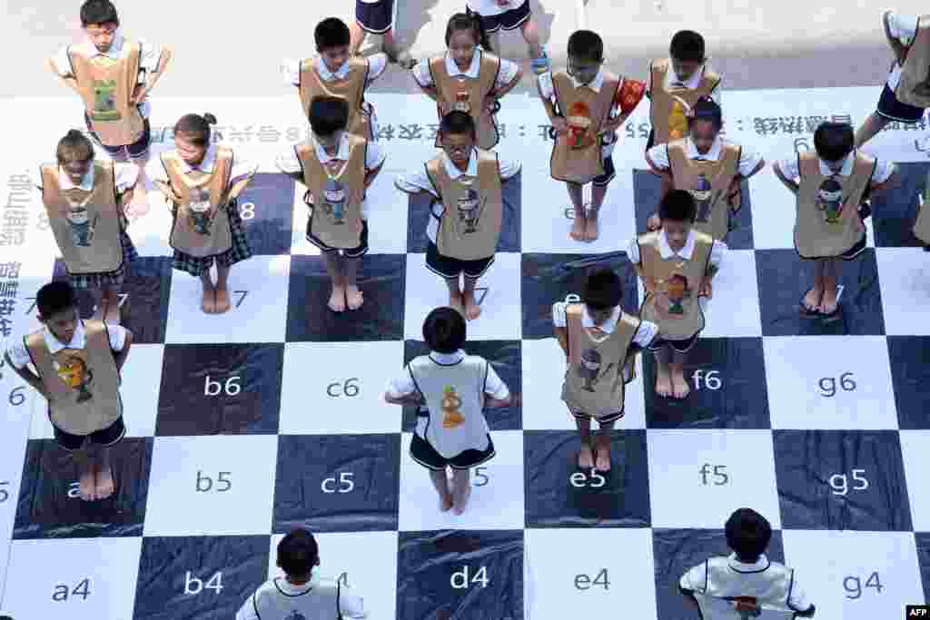 Anak-anak bermain catur di papan catur raksasa di sekolah dasar di Handan di provinsi Hebei yang terletak di bagian utara China.&nbsp; Pertandingan catur &ldquo;langsung&rdquo; dimainkan oleh 32 siswa untuk mempromosikan permainan catur di sekolah.